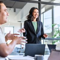 Image of three young people with laptops having a conversation by a window.