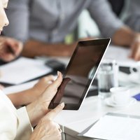 Image of a woman working on a tablet device in a classroom.